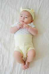 Cute newborn baby model wearing Avauma Baby Hug Setup in Lime Bloom. Adorable yellow baby romper on a white studio background.
